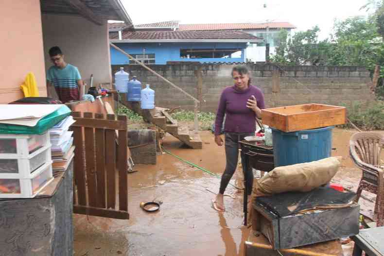 Moradora limpa a casa inundada de barro pela enxurrada