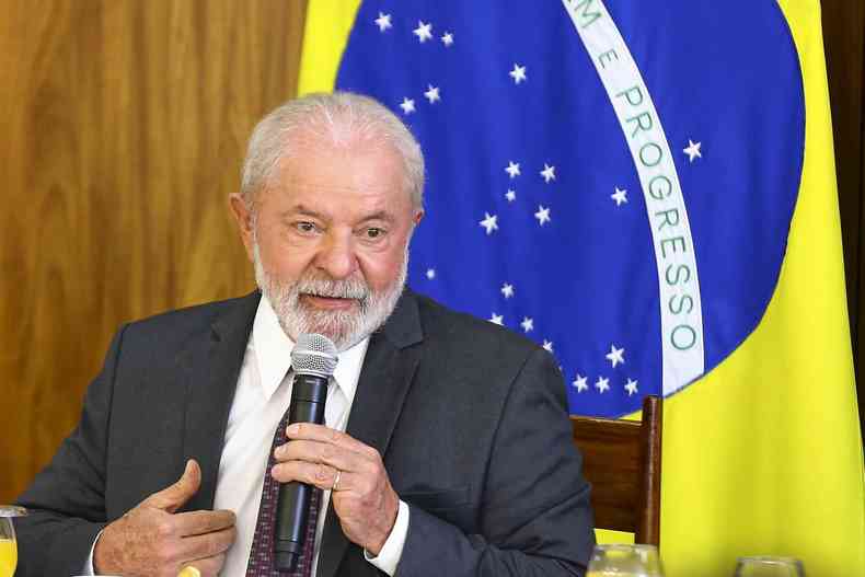 Lula fala ao microfone; atrs dele, uma bandeira do Brasil