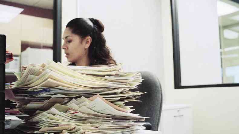 Mulher no escritrio com mesa cheia de documentos