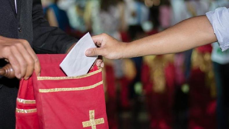 Pessoa colocando doa��o no saco de oferendas para a igreja