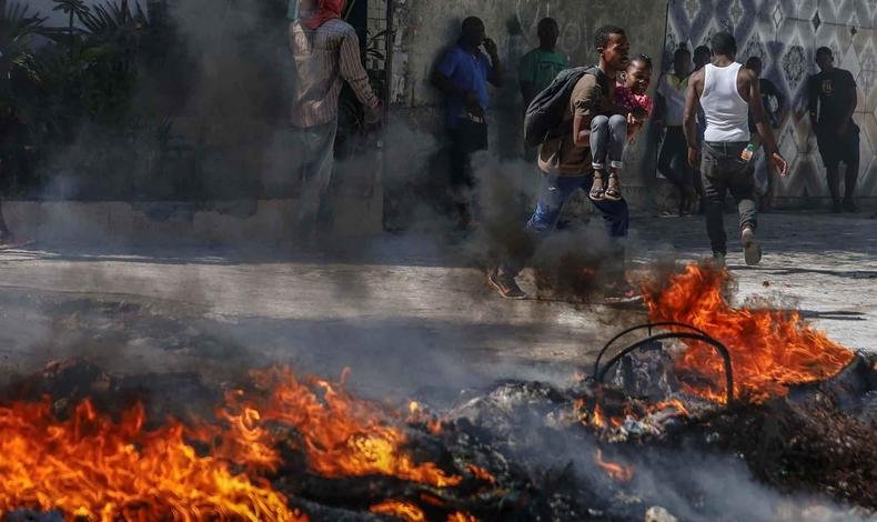 Fogo em primeiro plano, com pessoas ao fundo