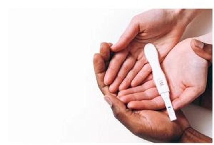 MOS FEMININAS BRANCAS SEGURANDO UM TESTE DE GRAVIDEZ SOBRE UMA MOS MASCULINA NEGRA