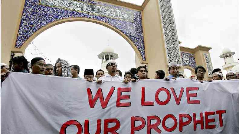 Manifestantes muulmanos exibem uma faixa professando seu amor pelo profeta Maom do lado de fora de uma mesquita antes de marchar em direo  embaixada dinamarquesa no centro de Kuala Lumpur