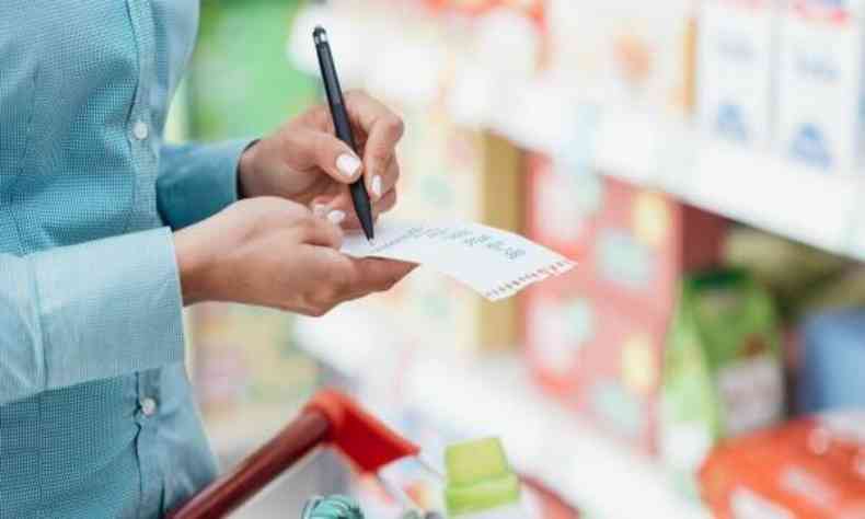 mulher anotando preos em supermercado