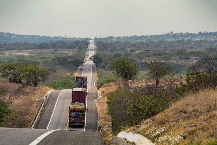 Caminh�es do Circo Spadoni cruzam imensa reta em dia ensolarado
