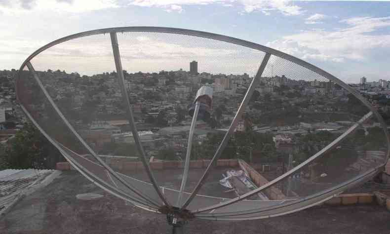 Antena parablica da cor prata apontando no fundo para uma cidade