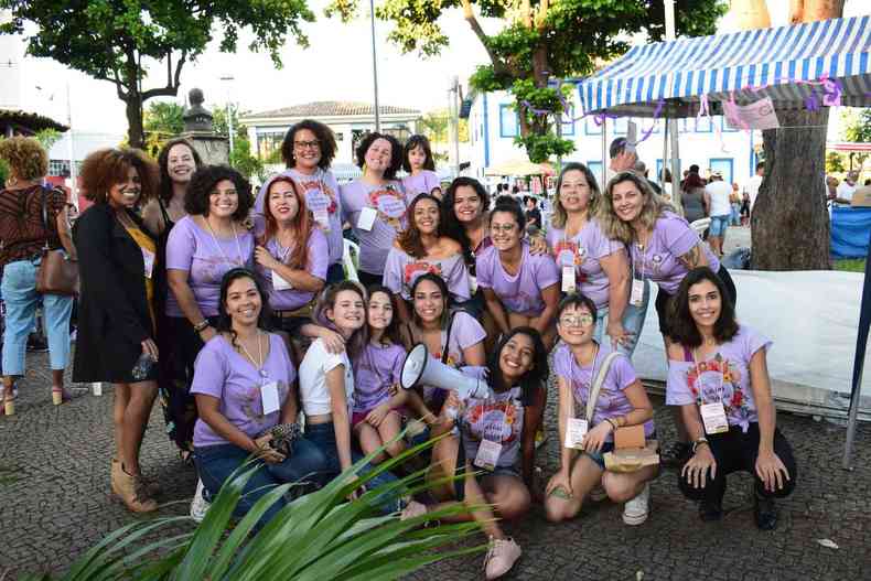 Mulheres reunidas e abraadas, com camisas lils.