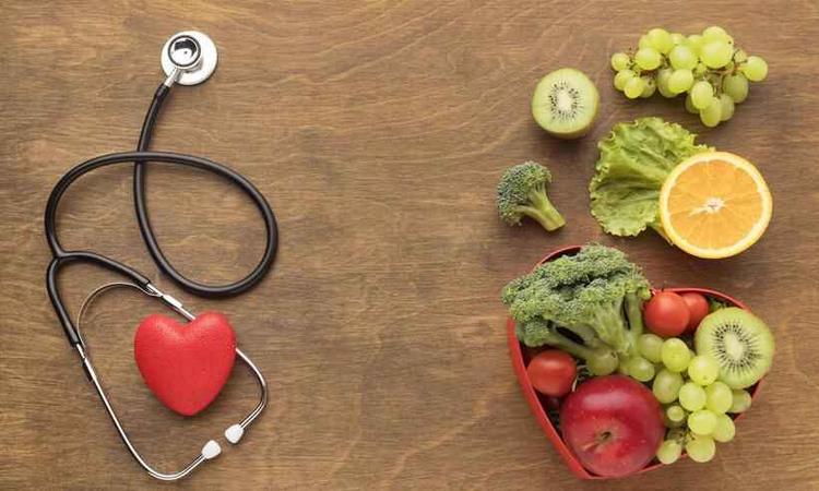 frutas e legumes ao lado de aparelho de estetoscópio com imagem de um coração