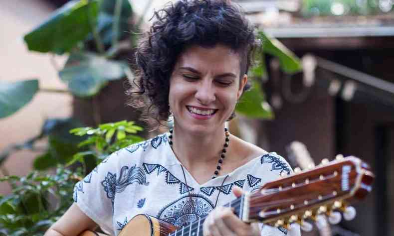 Instrumentista Camila Menezes toca viola caipira e sorri