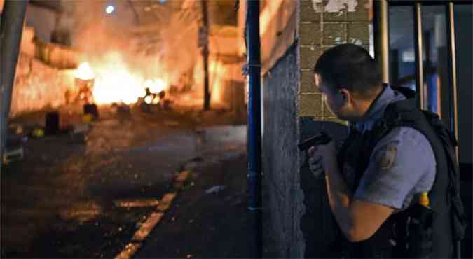 Policial empunha arma de munio letal durante protesto de moradores contra a morte de danarino no morro do Pavo-Pavozinho(foto: AFP PHOTO / CHRISTOPHE SIMON )