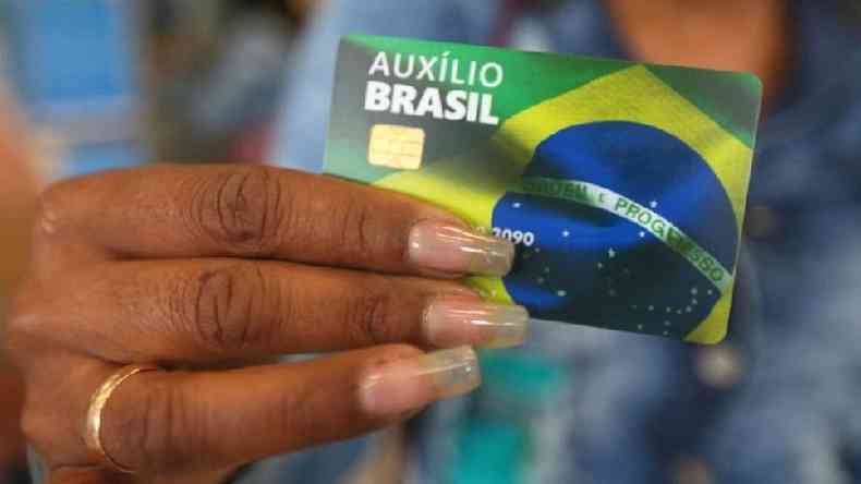 Mo feminina segurando carto do Auxlio Brasil ilustrado com a bandeira nacional