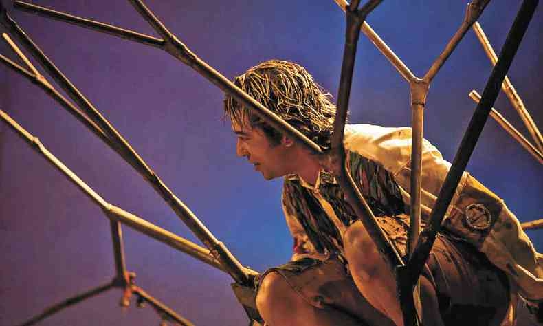 Em cena de 'Quase rvore', ator se ajoelha perto de estrutura que se assemelha aos galhos de uma rvore
