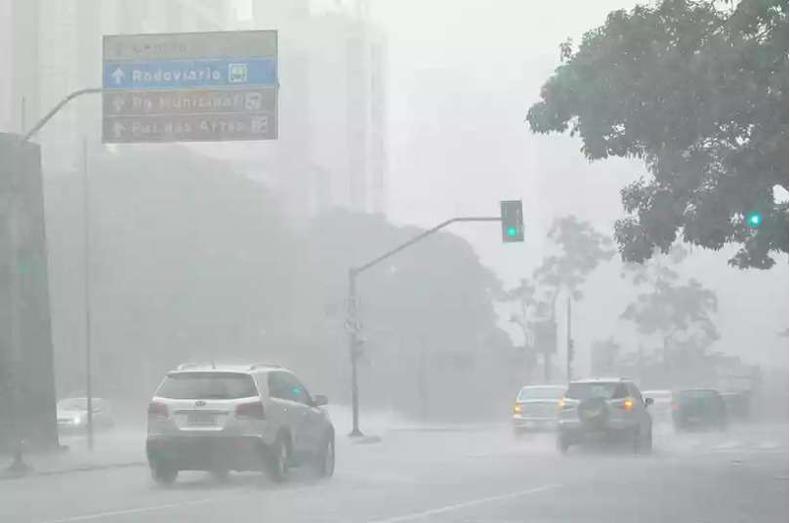 Carros passando em uma avenida sob forte chuva