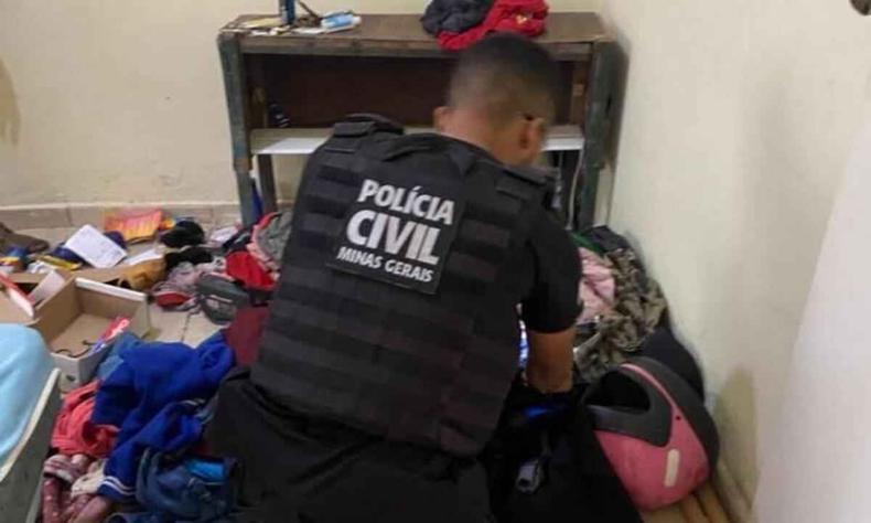 Policiais civis apreenderam na casa do suspeito um celular, a chuteira emprestada a ele por uma das vítimas e um par de uniforme do time feminino que ele treinava(foto: PCMG/Divulgação) Policial civil de costas revira itens diversos no chão de um quarto.
