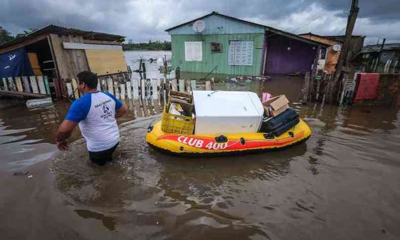 Morador carrega seus pertences em bote inflvel, no Bairro Vila Rica, em Gravata(foto: AFP PHOTO / JEFFERSON BERNARDES )