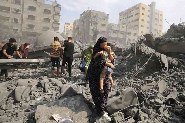 Mulher palestina com criana no colo evacua regio alvo de ataques de resposta de Israel, depois do massacre de 7/10