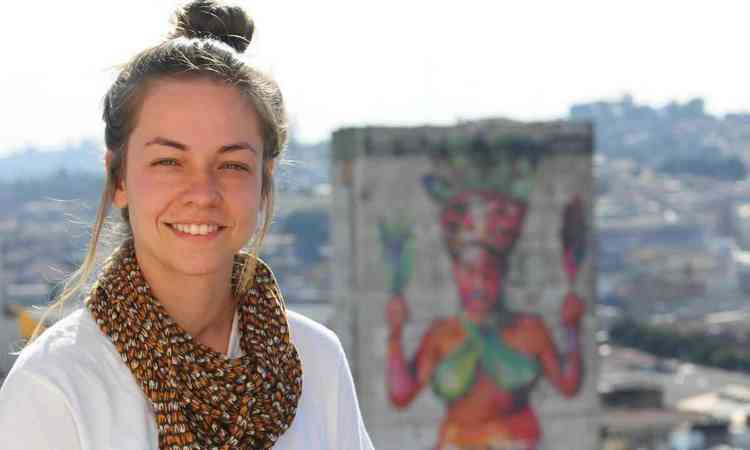 Priscilla Amoni sorri e ao fundo v-se prdio com mural grafitado, no Centro de BH