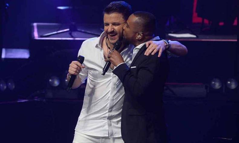 Mauricio Manieri est no palco, sorrindo, e recebe beijo do cantor Jon Secada 