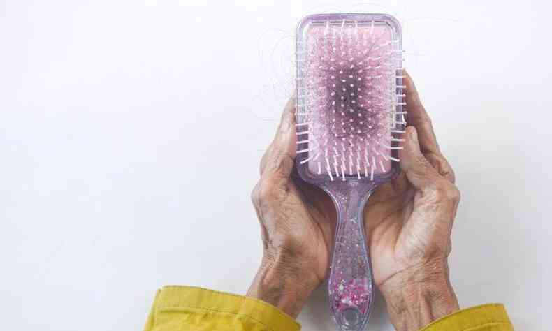 mos envelhecidas segura uma escova com vrios fios de cabelo
