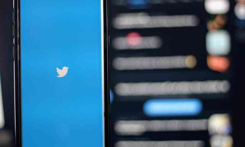 Celular com o logo do Twitter em frente a um computador com o Twitter aberto
