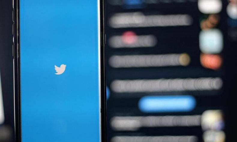 Celular com o logo do Twitter em frente a um computador com o Twitter aberto