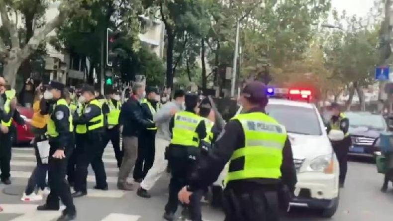 Uma equipe da BBC filmou confrontos entre policiais e manifestantes em Xangai no local de um protesto(foto: BBC) Policiais vestindo jaquetas fluorescentes confrontam manifestantes ao lado de um veículo em Xangai