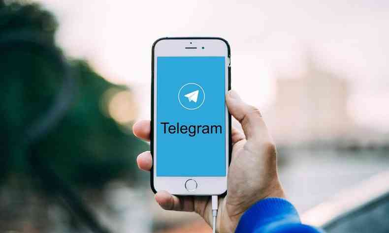 mo de um homem segura smartphone com o telegram na tela