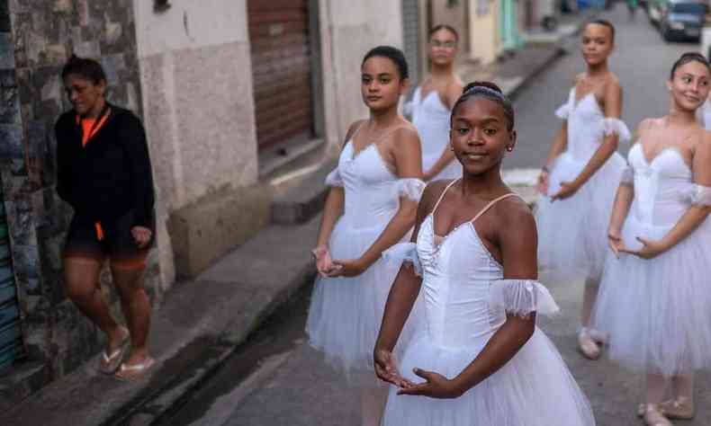 Meninas com figurinos brancos de bailarina com saias tchutchu danam em frente  escola de dana do Ballet Manguinhos, em favela carioca
