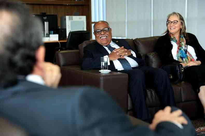 O ministro Benedito em seu gabinete no TSE. Ele est de terno azul escuro risca de giz e gravata azul, sentado em um sof marrom com as mos cruzadas sobre a barriga.