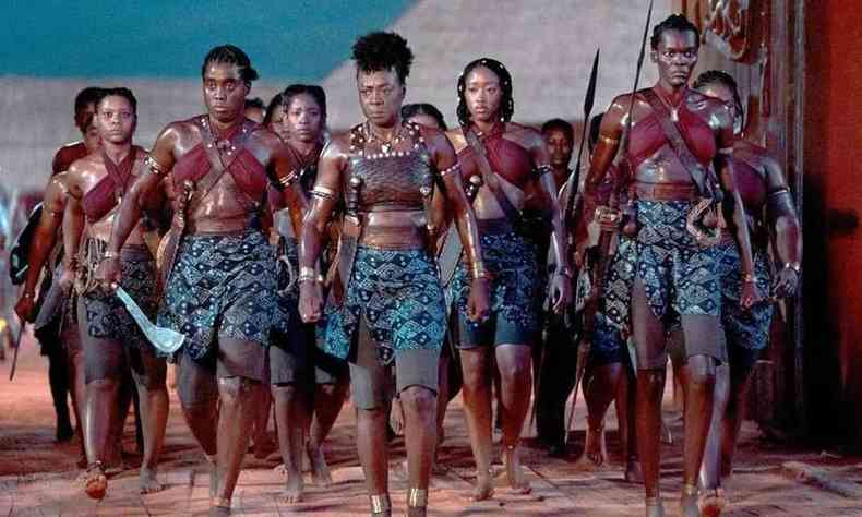 Foto mostra atrizes caracterizadas como guerreiras africanas andando em direção à câmera 
