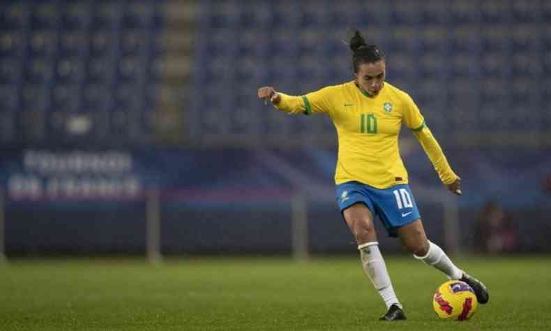Marta com uniforma da seleo brasileira chutando uma bola de futebol em campo