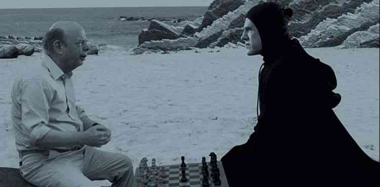 Atores Wallace Shawn e Christoph Waltz jogam xadrez, tendo praia ao fundo, no filme 'O festival do amor'