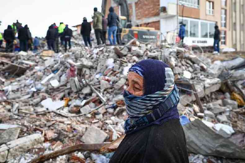 Uma mulher observa enquanto equipes de emergncia e moradores locais procuram sobreviventes no local de um prdio que desabou aps um grande terremoto no distrito de Elbistan, em Kahramanmaras, Turquia, 08 de fevereiro de 2023.