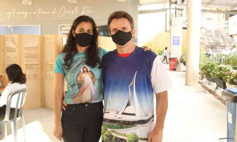 casal com camisas com motivos religiosos. ambos usam mscara
