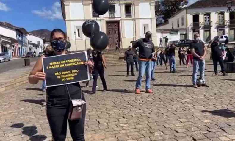 Vestidos de preto e empunhando cartazes, comerciantes protestaram em uma das praas da cidade(foto: WhatsApp/Reproduo)