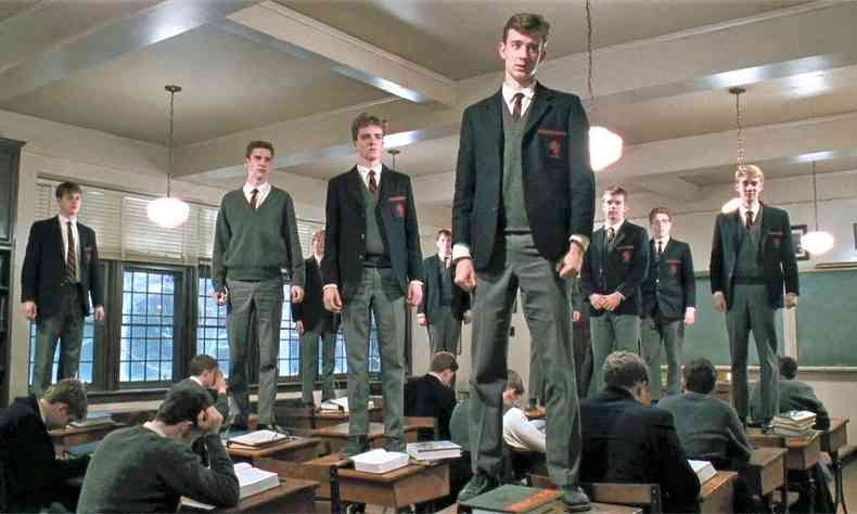 Rapazes em p sobre carteiras na sala de aula, em cena do filme Sociedade dos poetas mortos