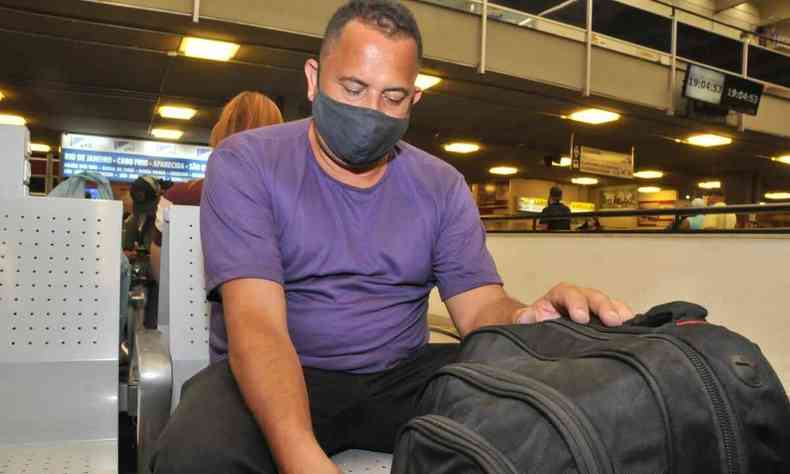 Cristiano Silva, 46 anos, sentado no hall de espera da rodoviária de BH enquanto mexe em sua mala