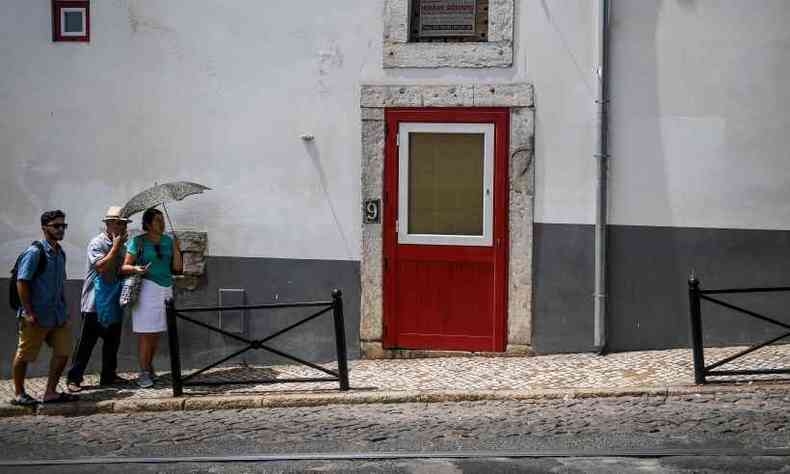 Turista tenta se proteger do sol com um guarda chuva no bairro de Alfama, em Lisboa(foto: Patricia de Melo MOreira/AFP )