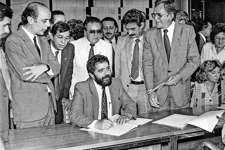 Lula à mesa, cercado por personalidades políticas que foram constituintes como ele, em 1988(foto: lula.com.br) Lula à mesa, cercado por personalidades políticas que foram constituintes como ele, em 1988