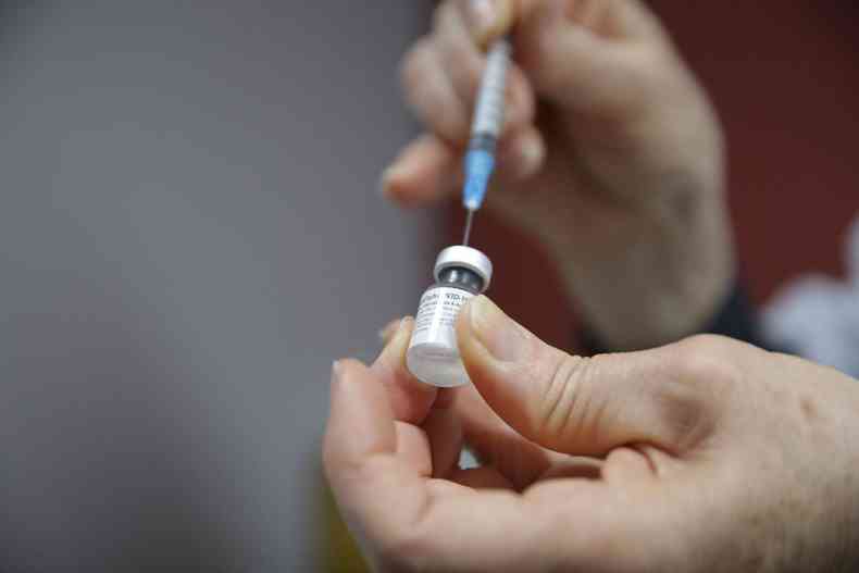 Mos seguram seringa e frasco de vacina da Pfizer