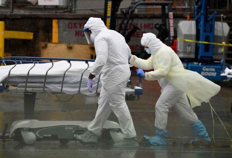 Equipe m�dica leva para o caminh�o frigor�fico o corpo de mais uma v�tima do coronav�rus em Nova York(foto: Angela Weiss/AFP)