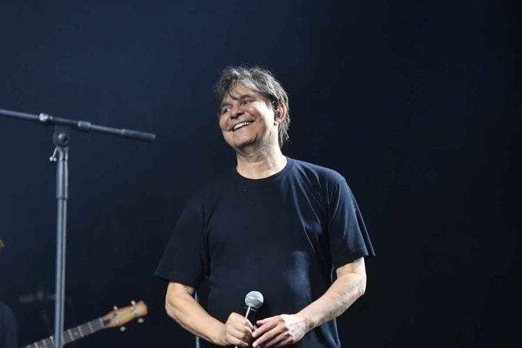 De camisa preta, com microfone na m�o, L� Borges sorri no palco
