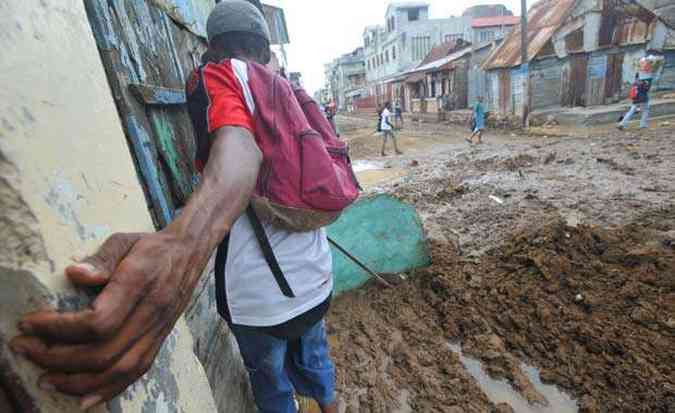 Haitiano tenta atravessar rua destruda pelas chuvas na cidade de Vertieres, a mais de 270 quilmetros de Porto Prncipe(foto: AFP PHOTO / THONY BELIZAIRE )