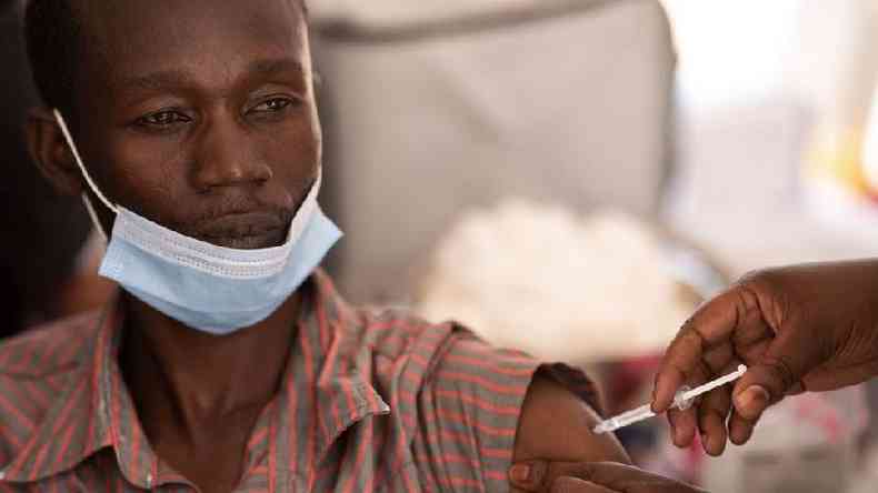 Homem negro com mscara, sendo vacinado