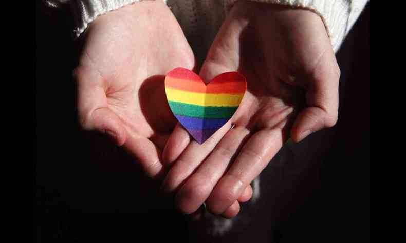 Mos segurando um corao pintado com as cores da bandeira LGBT