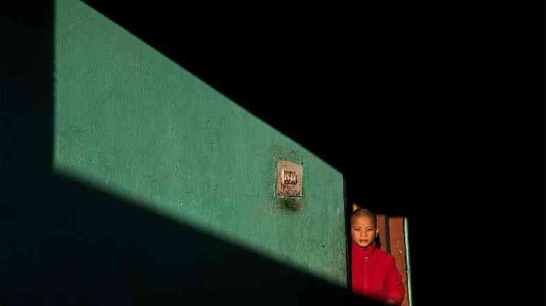 Um menino olha por uma porta no Buto