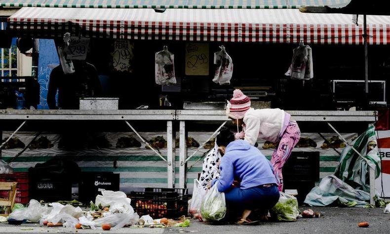 Mulher e criança buscam restos de alimentos em feira no Jaçanã, em SP(foto: Rubens Cavallari/Folhapress) Mulher e criança buscam restos de alimentos em feira no Jaçanã, em SP