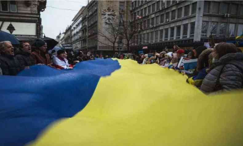 Pessoas protestam com a bandeira da Ucrnia 