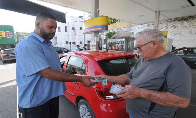 homem pagando frentista em posto de gasolina 