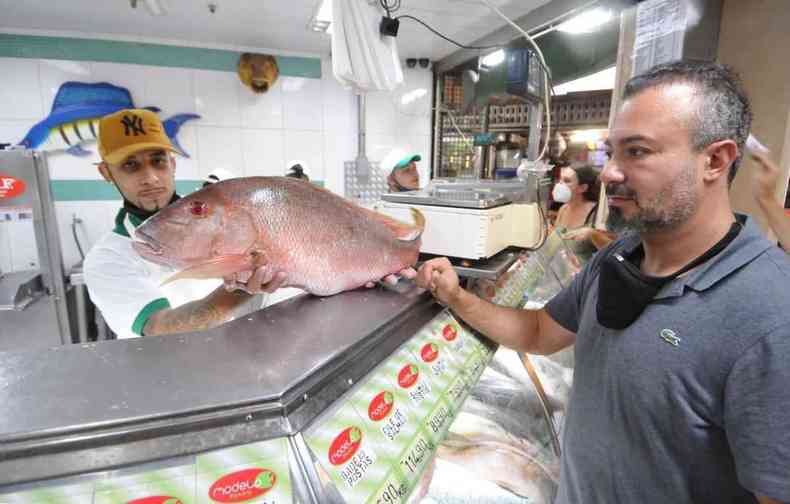 O empresrio Cristiano Machado olha o peixe Namorado na mo do vendedor 
